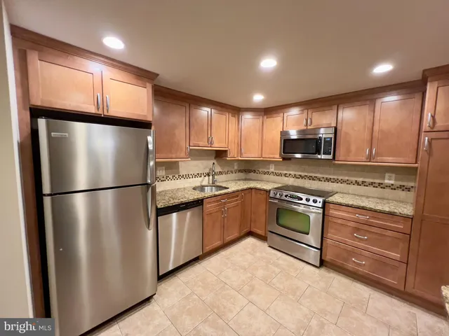 a kitchen with granite countertop stainless steel appliances a refrigerator sink and microwave