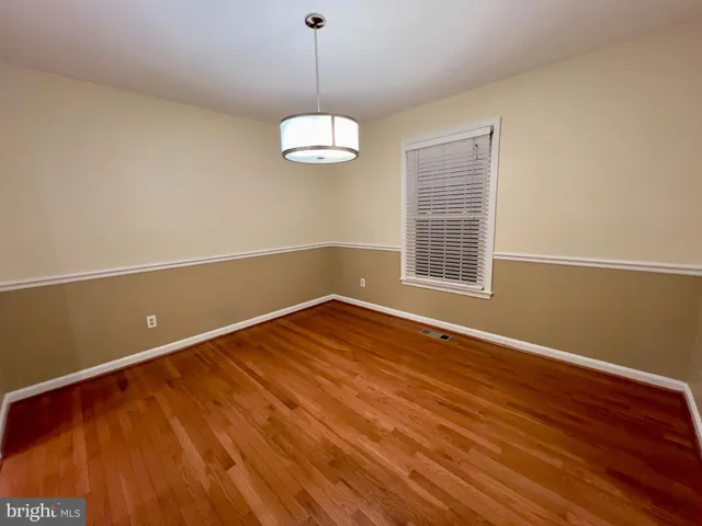 a view of empty room with wooden floor and window