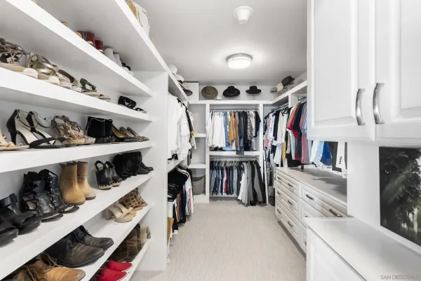 a view of walk in closet with clothes and shoes