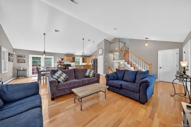 a living room with furniture kitchen view and a wooden floor