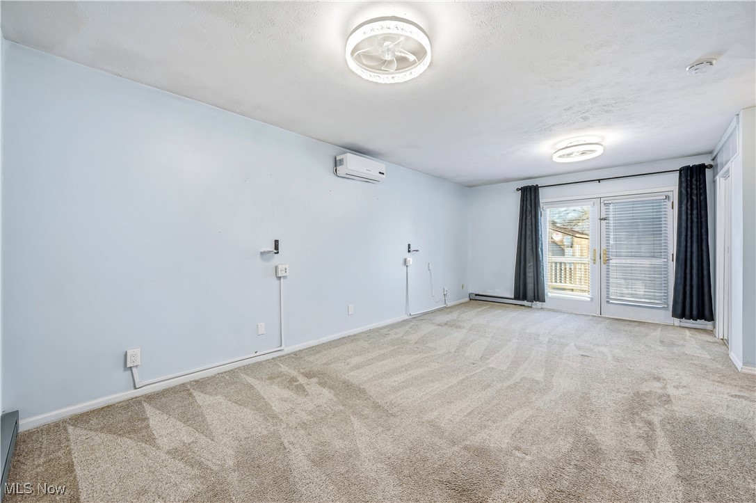 245 North Road Niles, OH 44446 - Photo 17 of 45 Carpeted spare room featuring a wall mounted AC, a baseboard radiator, and a textured ceiling