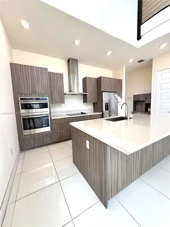 a kitchen with kitchen island granite countertop a sink counter top space appliances and cabinets