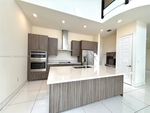 a large kitchen with kitchen island a large counter top stainless steel appliances and cabinets