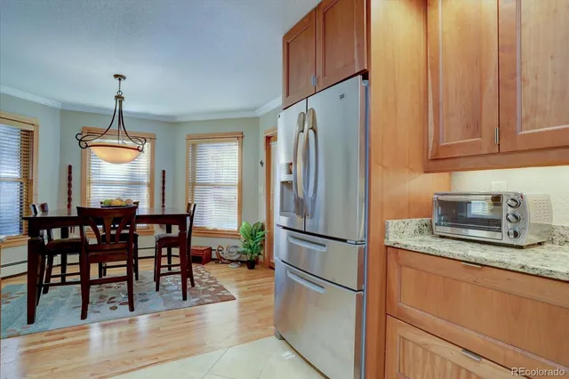 a kitchen with stainless steel appliances granite countertop a refrigerator a stove a dining table and chairs