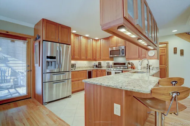 a kitchen with stainless steel appliances granite countertop a refrigerator a sink a stove a dining table and chairs