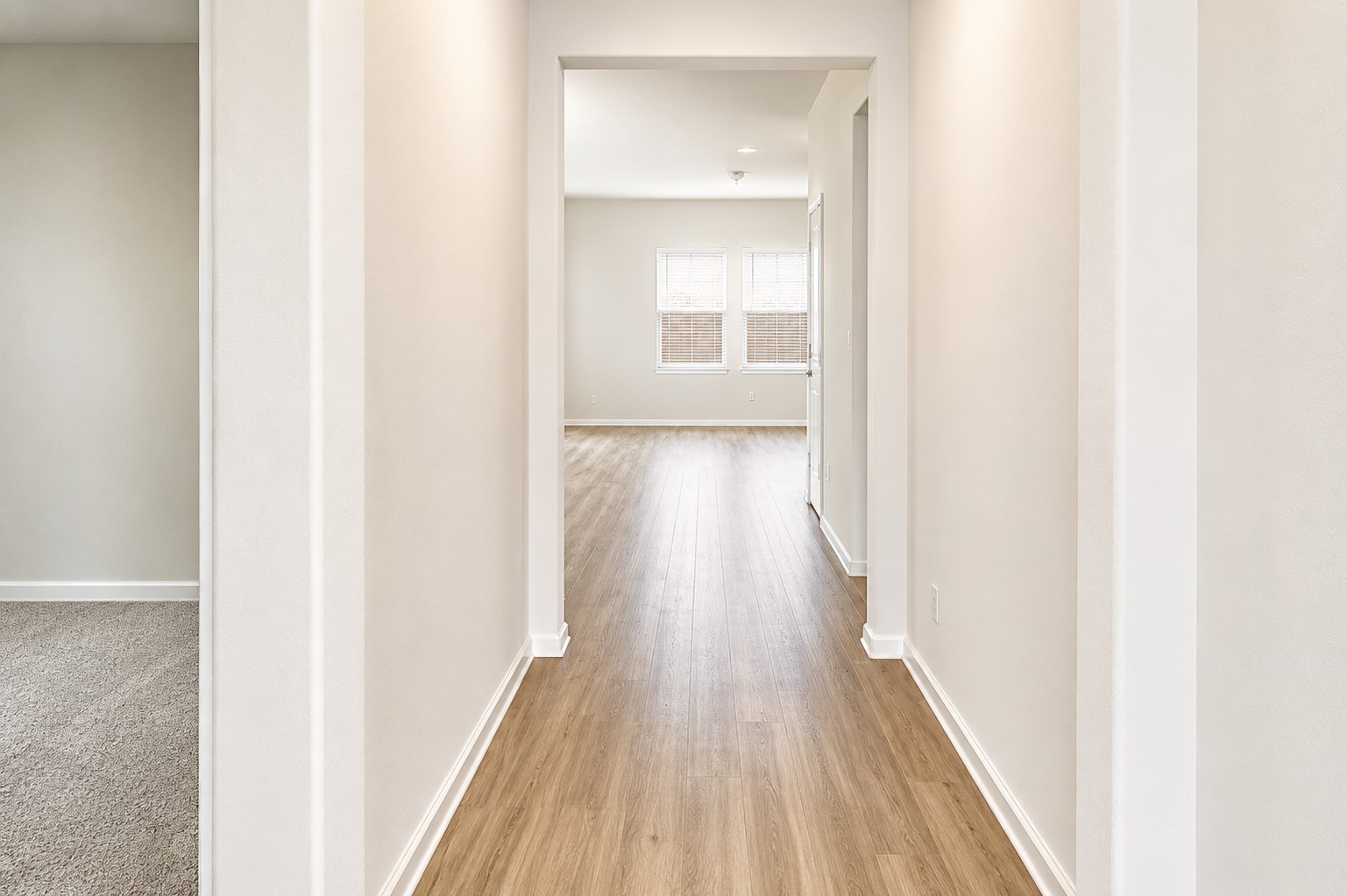 828 Mallow Road Leander, TX 78641 - Photo 3 of 14 A long, bright hallway extends towards a sun-filled room with natural light streaming through windows.