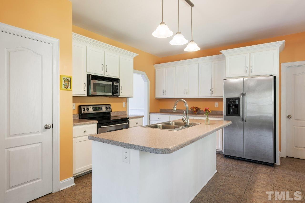 135 Cattle Farm Drive Raleigh, NC 27603 - Photo 12 of 30 a kitchen with a sink a refrigerator a stove a microwave and cabinets