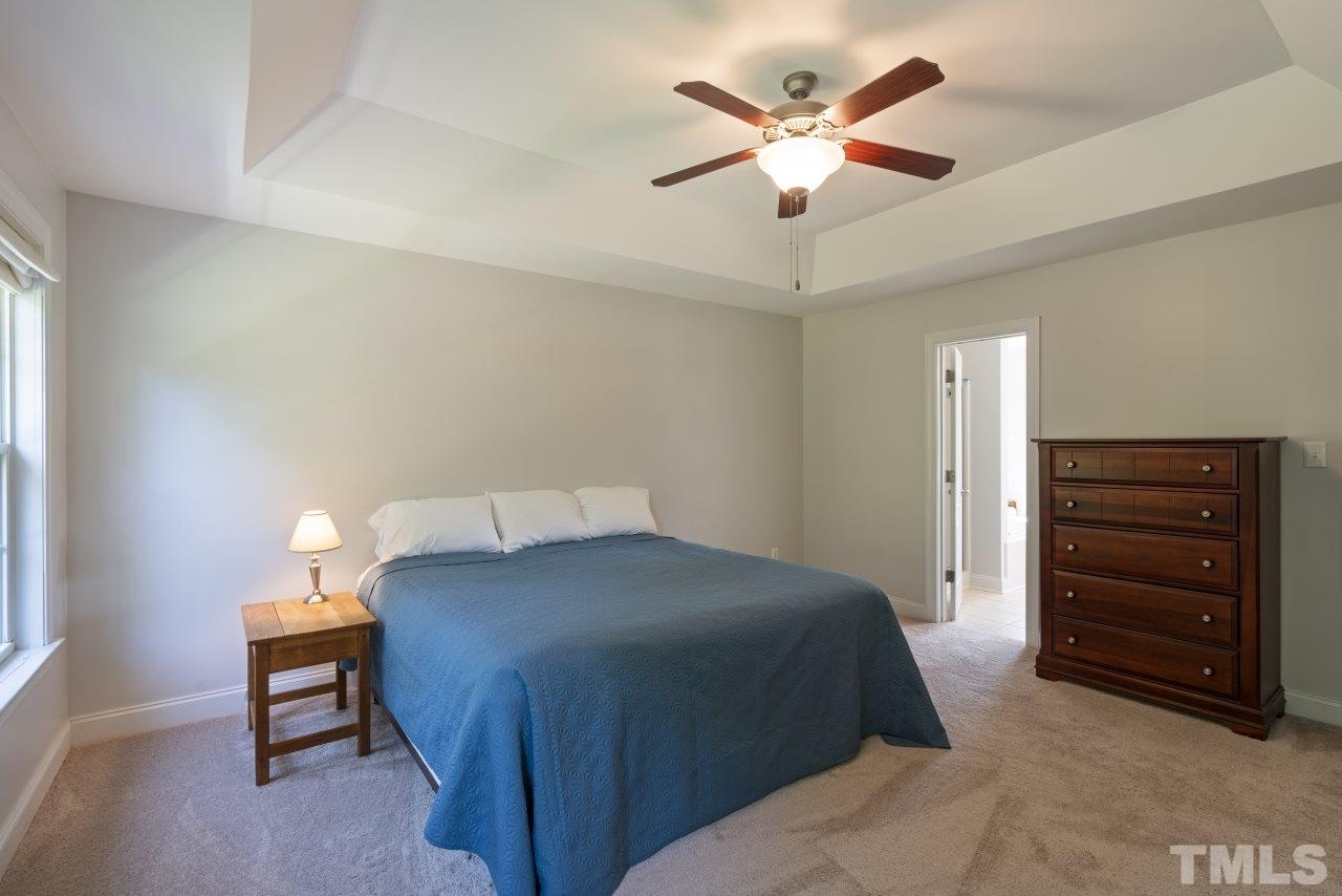 135 Cattle Farm Drive Raleigh, NC 27603 - Photo 14 of 30 a bedroom with a bed and a chandelier