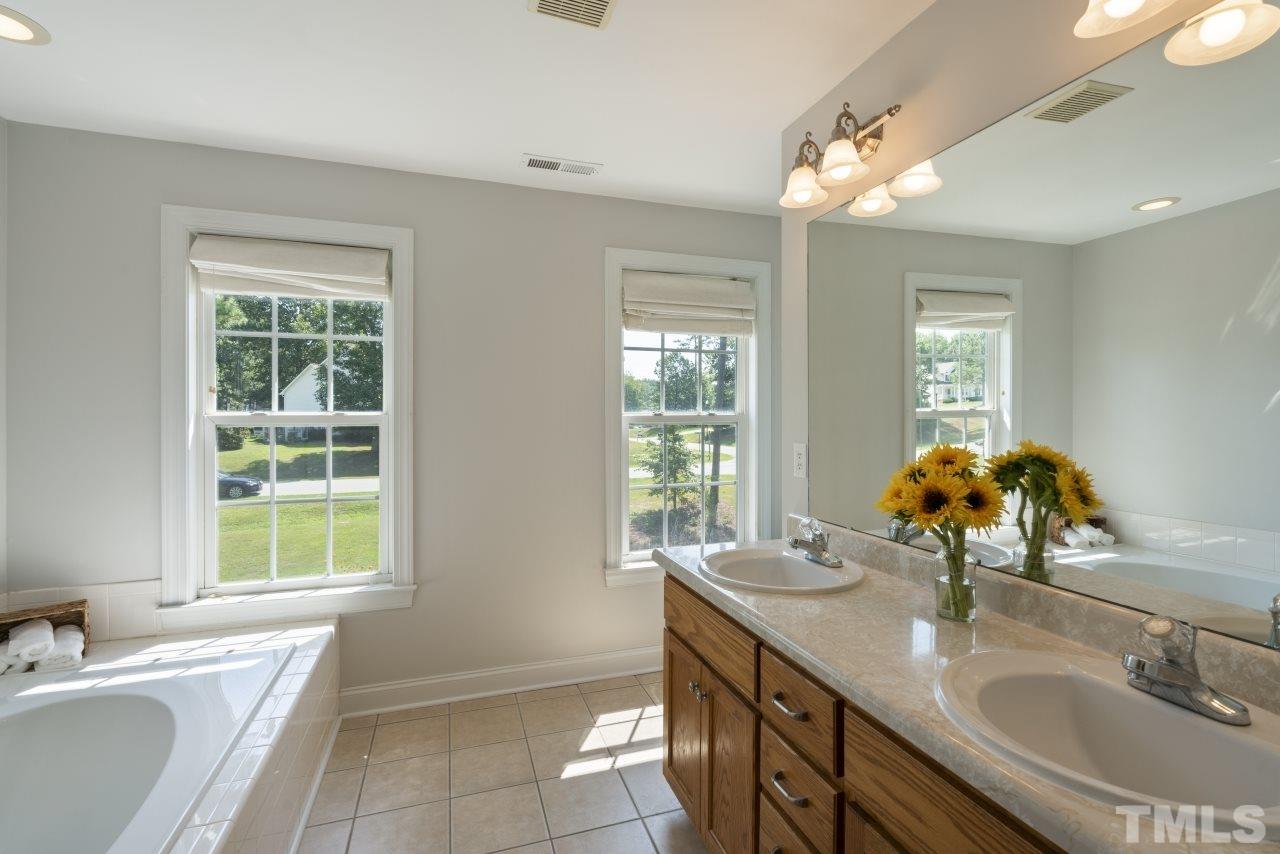 135 Cattle Farm Drive Raleigh, NC 27603 - Photo 16 of 30 a bathroom with a double vanity sink bathtub and next to a window
