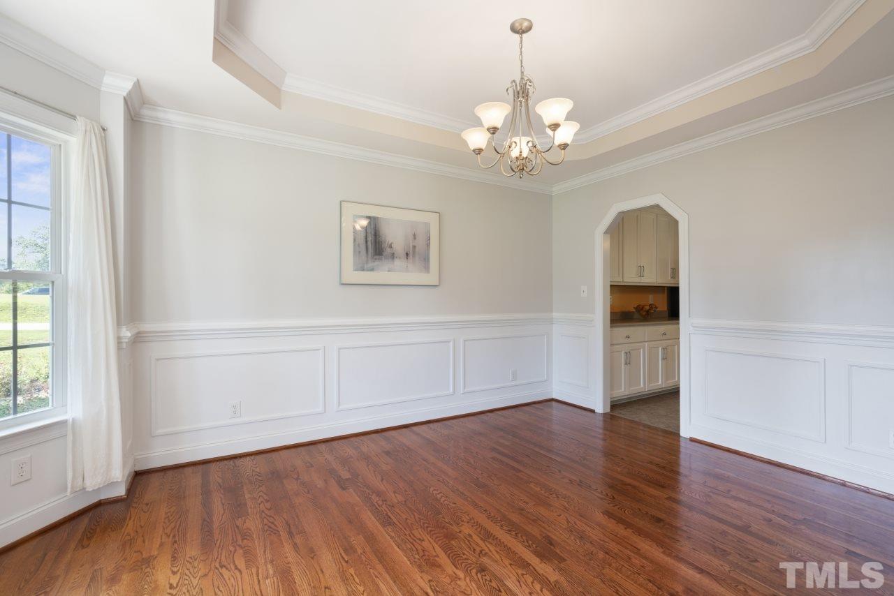 135 Cattle Farm Drive Raleigh, NC 27603 - Photo 7 of 30 an empty room with wooden floor chandelier and windows