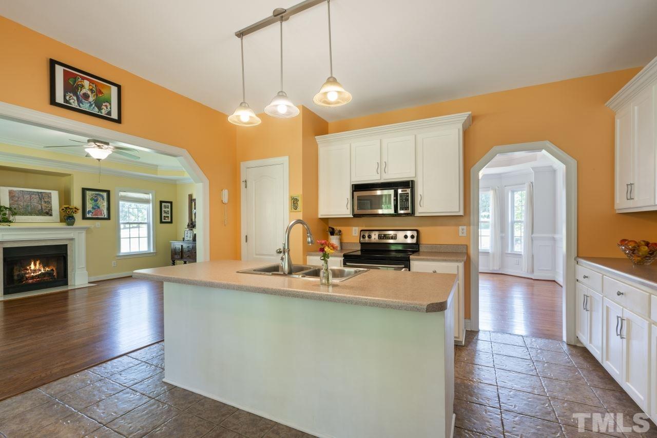 135 Cattle Farm Drive Raleigh, NC 27603 - Photo 9 of 30 a kitchen with stainless steel appliances granite countertop a sink a stove top oven a chimney cabinets and wooden floor