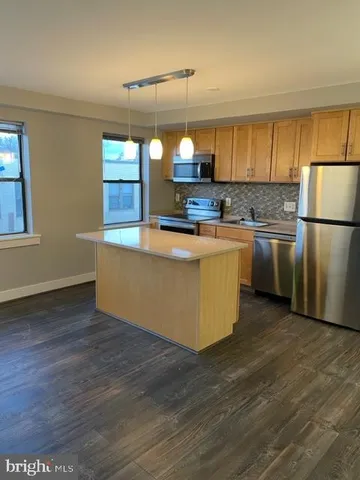 a kitchen with kitchen island a sink wooden floor and stainless steel appliances