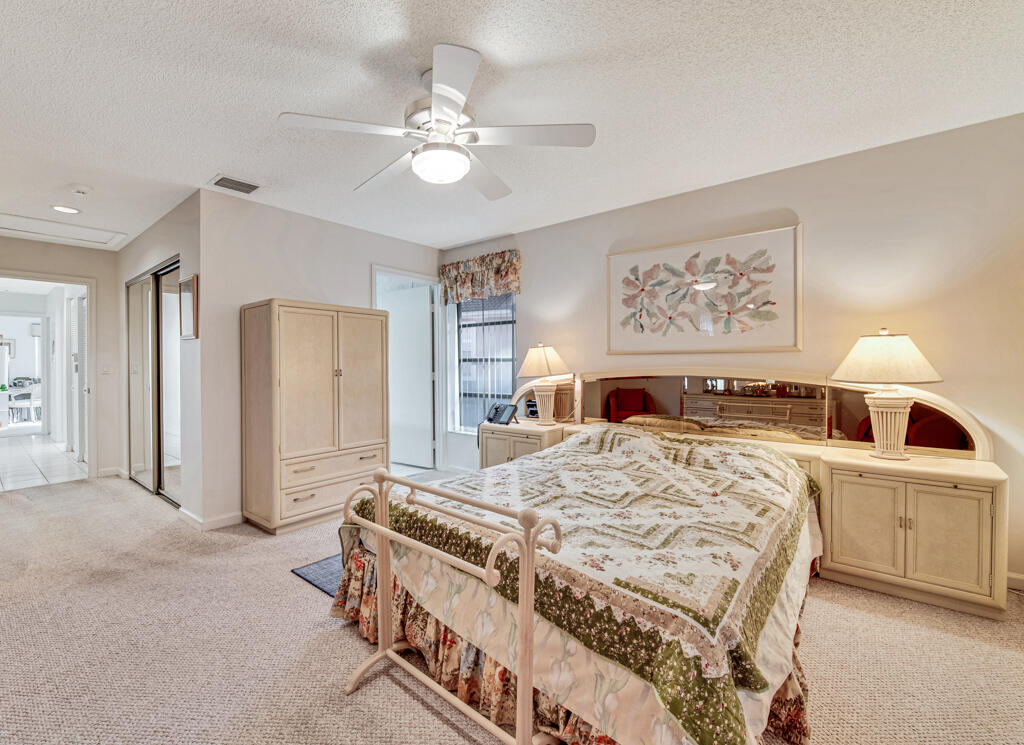 9976 Seacrest Circle, Unit A Boynton Beach, FL 33437 - Photo 19 of 48 a spacious bedroom with a bed and a chandelier