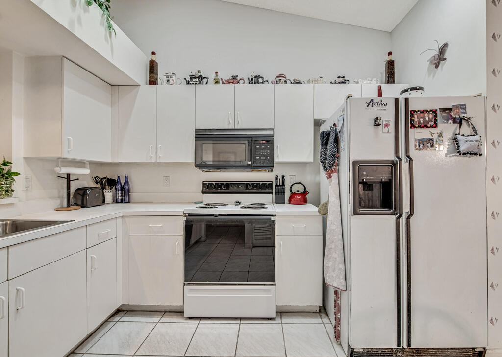 9976 Seacrest Circle, Unit A Boynton Beach, FL 33437 - Photo 9 of 48 a kitchen with stainless steel appliances a refrigerator sink and cabinets