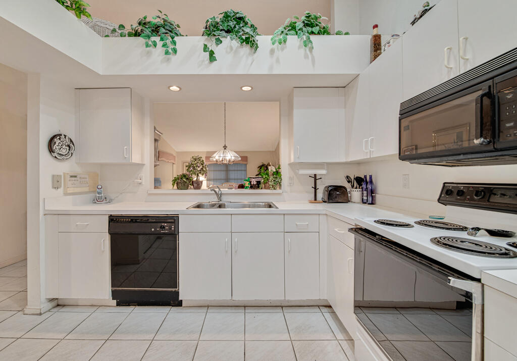 9976 Seacrest Circle, Unit A Boynton Beach, FL 33437 - Photo 10 of 48 a kitchen with a sink white stove and white cabinets