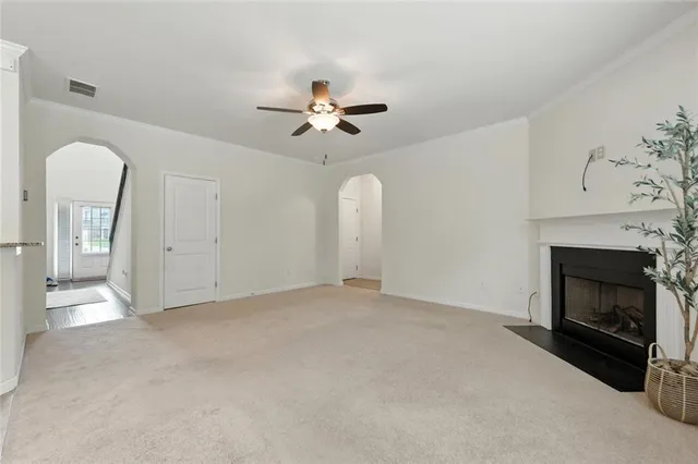 a view of an empty room with chandelier fan and fire place