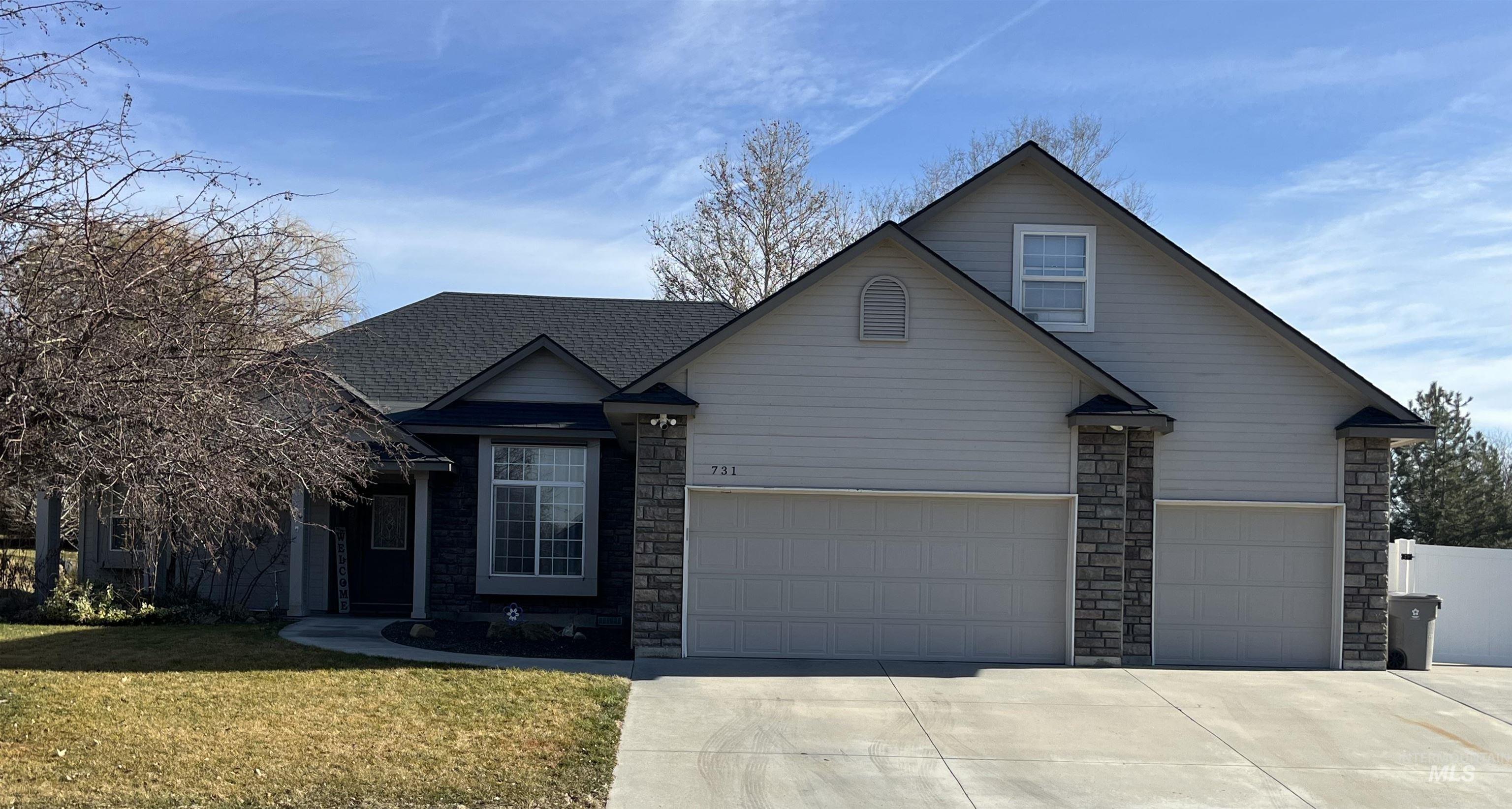 Traditional home with concrete driveway, a front yard, and stone siding