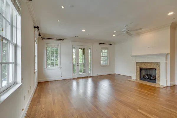 an empty room with wooden floor fireplace and windows