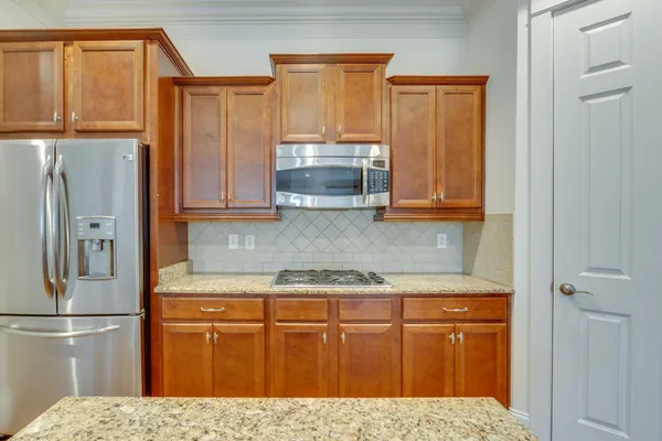 a kitchen with stainless steel appliances granite countertop a refrigerator and a stove top oven