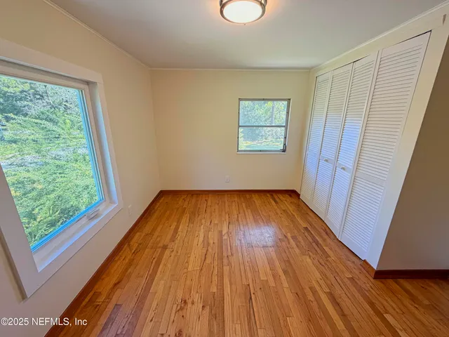 a view of empty room with wooden floor and fan