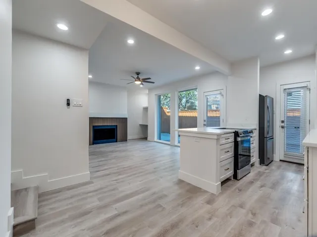 an empty room with kitchen and fireplace