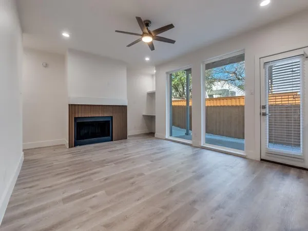 an empty room with wooden floor a ceiling fan and a fireplace
