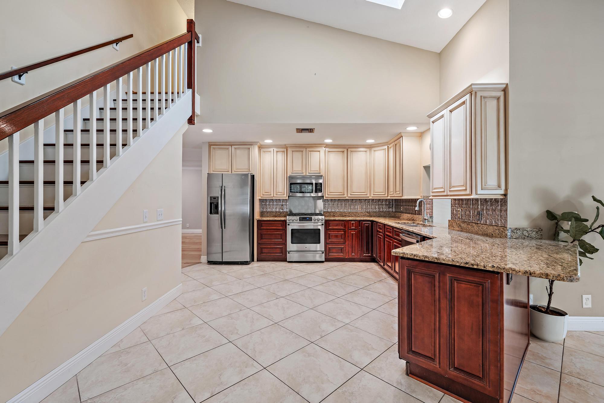 19150 Southeast Jupiter Road Jupiter, FL 33458 - Photo 11 of 43 a kitchen with stainless steel appliances kitchen island granite countertop a refrigerator a stove and a sink with cabinets