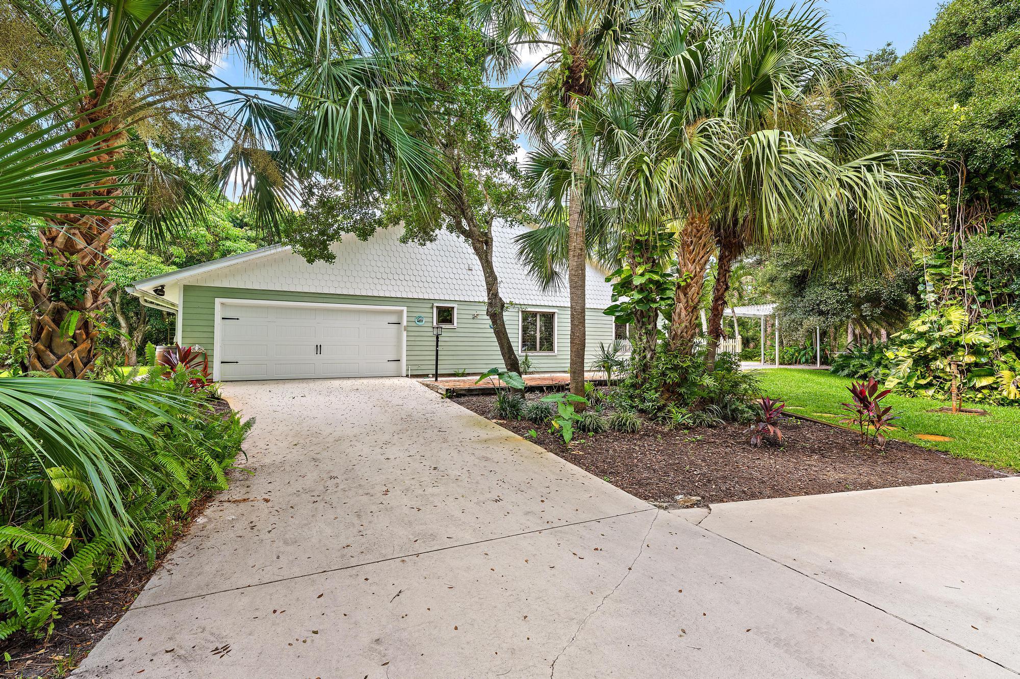 19150 Southeast Jupiter Road Jupiter, FL 33458 - Photo 33 of 43 a front view of a house with a garden and a tree