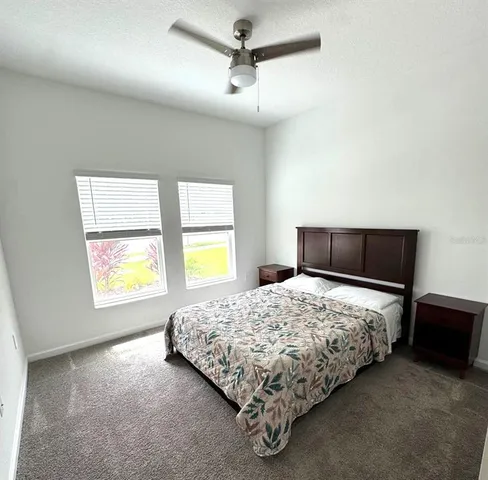 a bedroom with a bed and two window