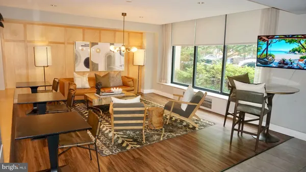 a view of a dining room with furniture one side kitchen view and wooden floor