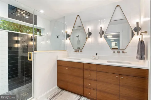 a bathroom with double vanity sink and two mirror