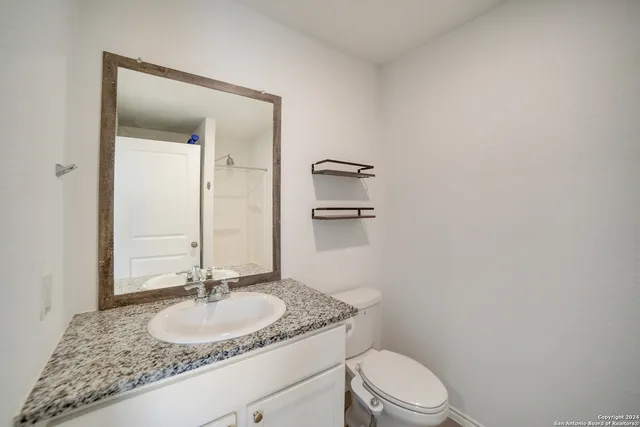 a bathroom with a granite countertop sink mirror vanity and toilet