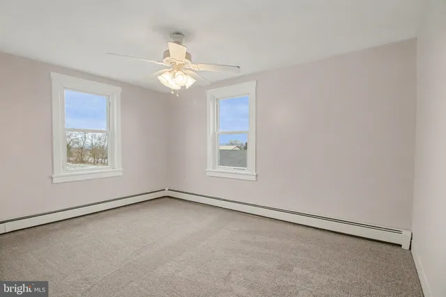 an empty room with a window and a fan
