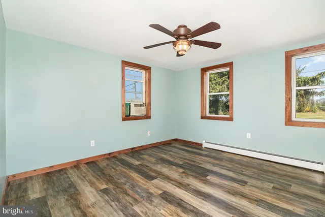 a view of a big room with wooden floor and windows