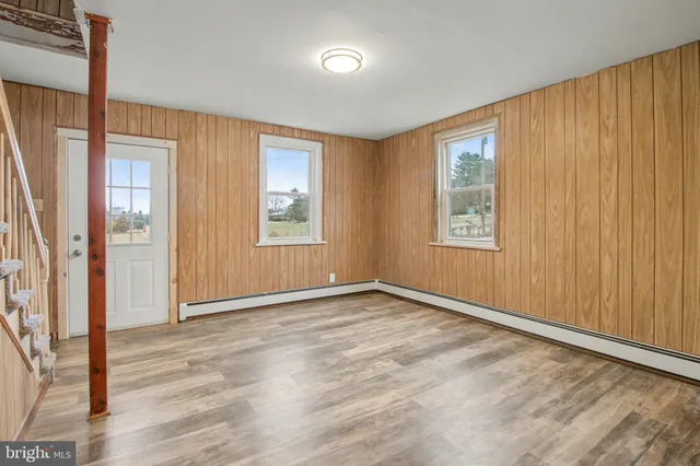 an empty room with wooden floor and windows