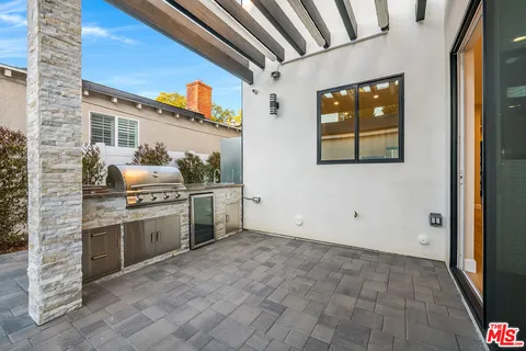 a living room with stainless steel appliances furniture a rug and a kitchen view
