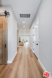 a view of a hallway with wooden floor and chandelier