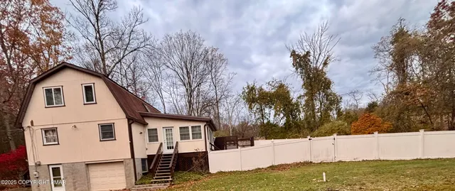 a view of a white house with a yard and large tree