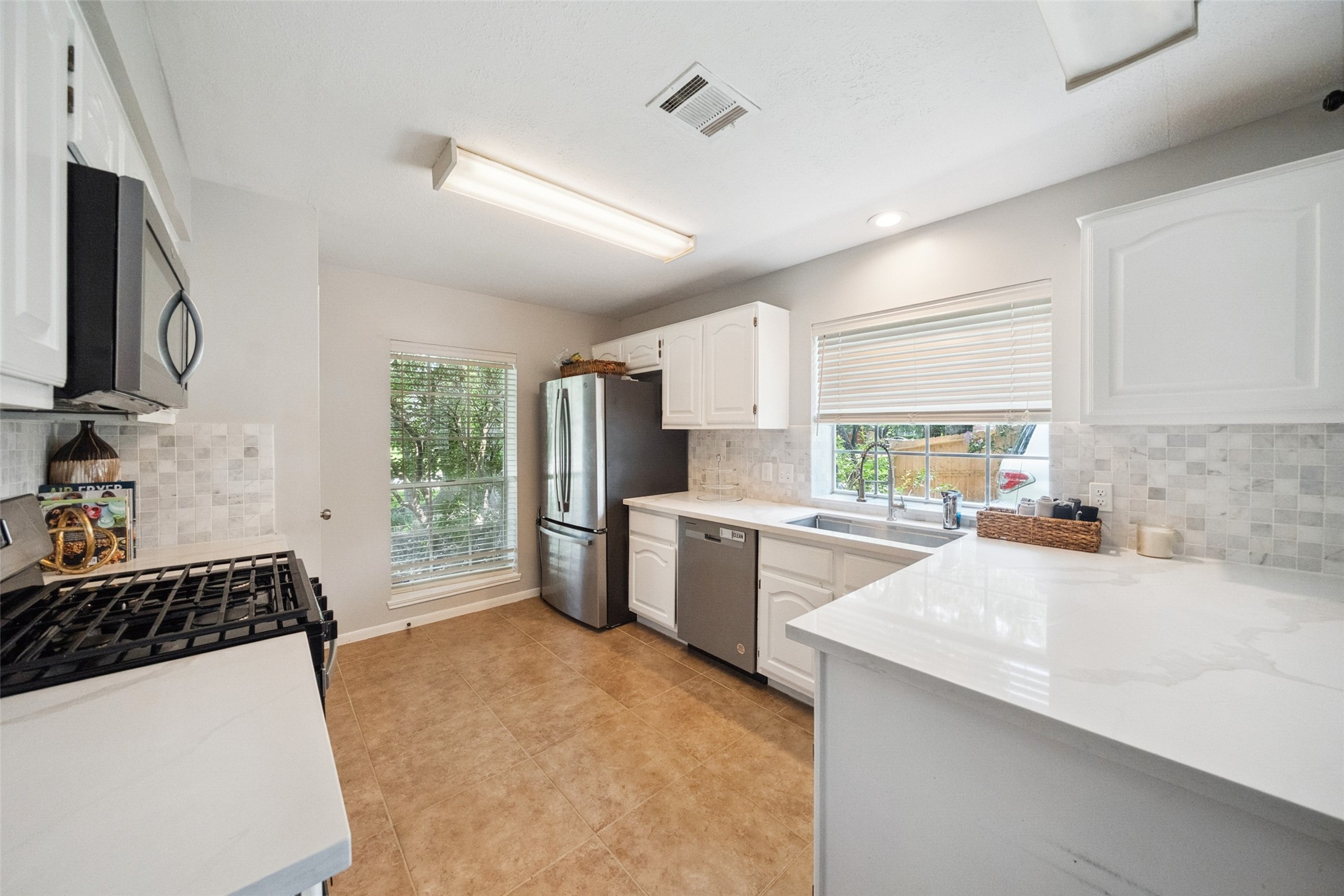 20407 Weald Way Street Spring, TX 77388 - Photo 9 of 31 a kitchen with a sink a stove a refrigerator cabinets and a counter top space