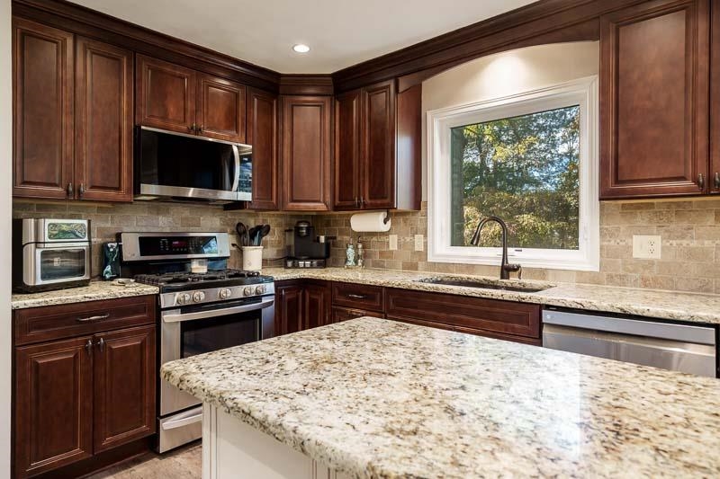 11948 Southgate Road Roscoe, IL 61073 - Photo 23 of 73 a kitchen with stainless steel appliances granite countertop a stove top oven a sink dishwasher and a microwave oven with cabinets