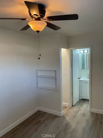 an empty room with wooden floor closet and windows