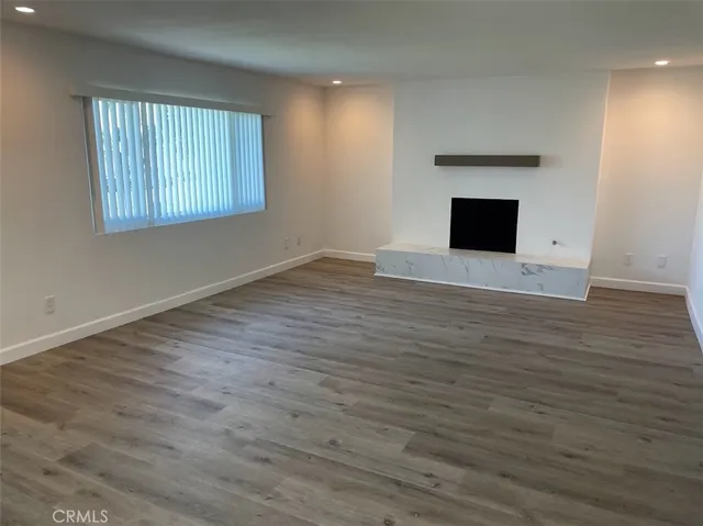 an empty room with wooden floor fireplace and windows