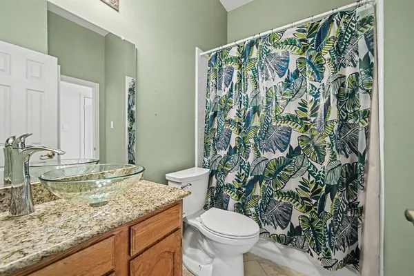 a bathroom with a granite countertop sink and a toilet