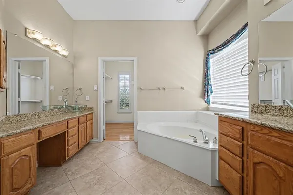 a spacious bathroom with a granite countertop tub sink and mirror