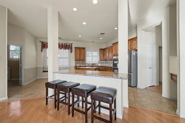 a kitchen with stainless steel appliances kitchen island granite countertop a refrigerator and a stove top oven