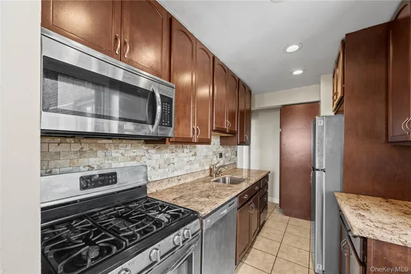 a kitchen with stainless steel appliances granite countertop wooden cabinets and a stove top oven