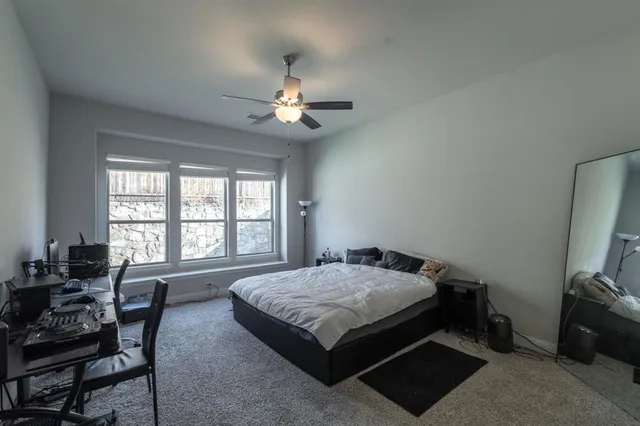 a spacious bedroom with a bed a couch and a flat tv screen on the dresser