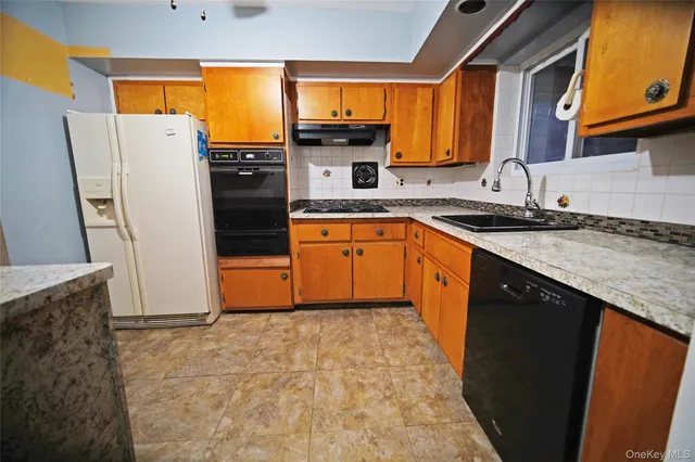 a kitchen with granite countertop a refrigerator a sink a stove top oven and a dining table