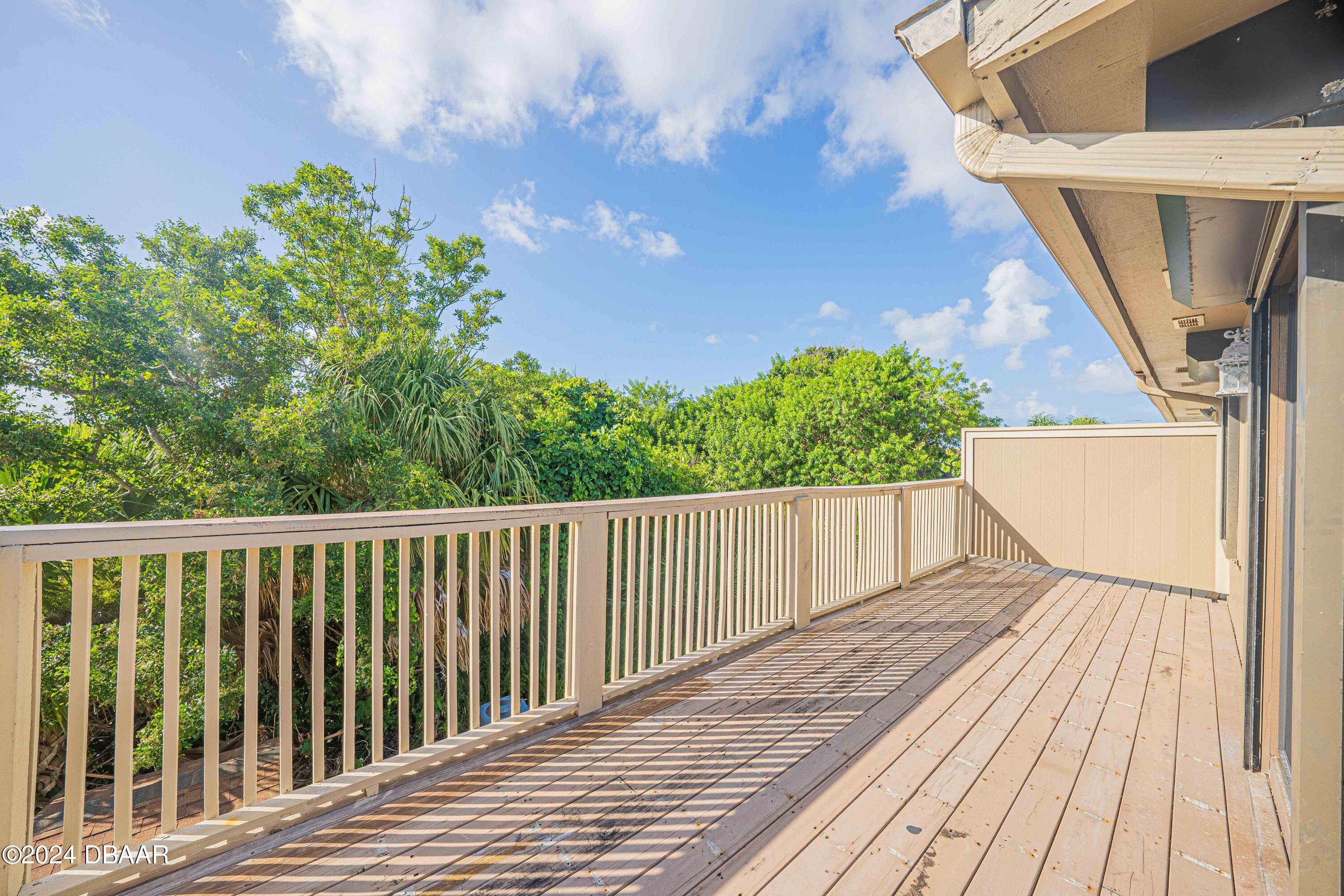 42 Jana Drive Ponce Inlet, FL 32127 - Photo 11 of 34 a balcony with wooden floor and trees in the background
