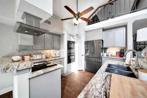a kitchen with granite countertop stainless steel appliances a refrigerator a stove a sink and white cabinets